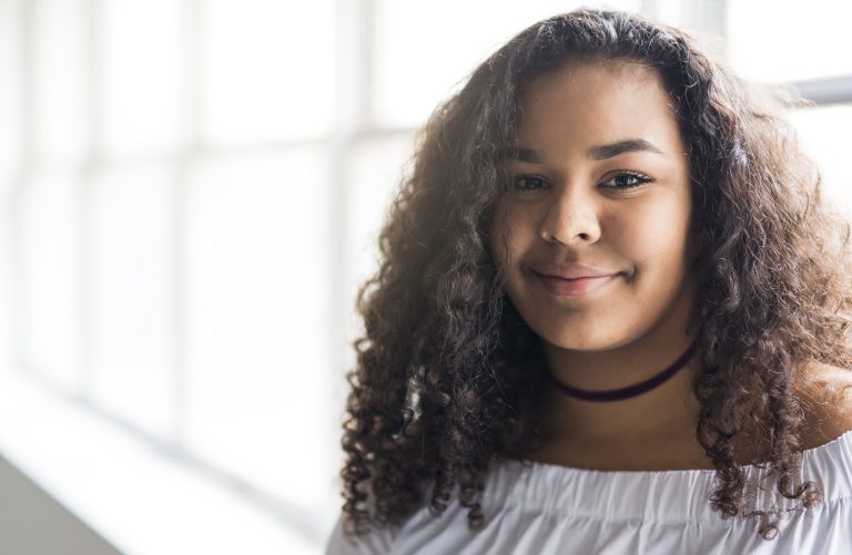 young woman in shirt with curly hair looking at the camera