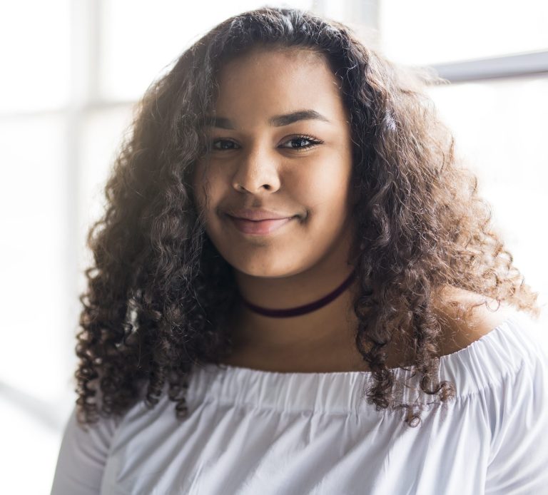 young woman in shirt with curly hair looking at the camera