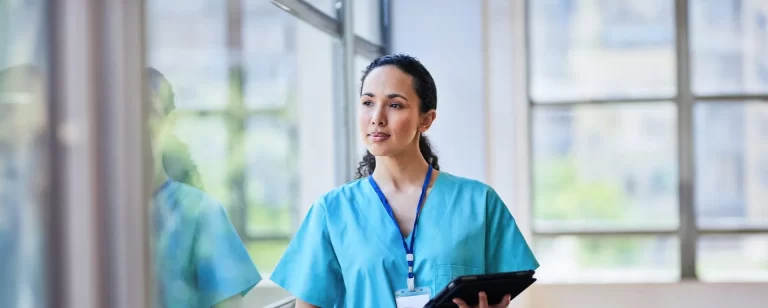 nurse in blue scrubs holding a clipboard